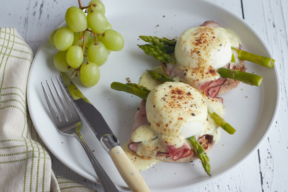 breakfast, eggs, plate, benedict, dish, food, ham, brunch, poached, muffin, hollandaise, meal, toast, bread, asparagus, vegetable, gourmet, grapes, fruit, knife, fork