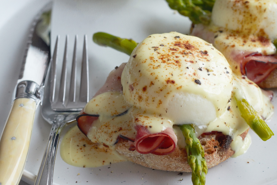 breakfast, eggs, plate, benedict, dish, food, ham, brunch, poached, muffin, hollandaise, meal, toast, bread, asparagus, vegetable, gourmet, grapes, fruit, knife, fork